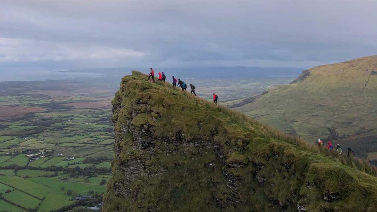 group of people walking up mountain to edge hiking adventure